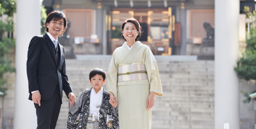 神社で七五三のお参りをする羽織袴姿の男の子と着物姿の母親・スーツ姿の父親の家族