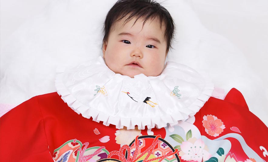 赤い掛け着に白いフリル襟を合わせたお宮参りの赤ちゃん