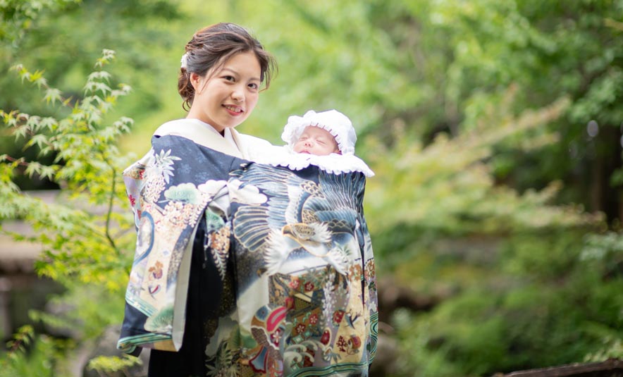 訪問着姿の母親が産着に包んだ赤ちゃんを抱くお宮参りの記念写真