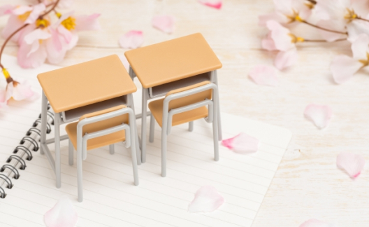 桜の花びらに囲まれた教室の机と椅子のミニチュア
