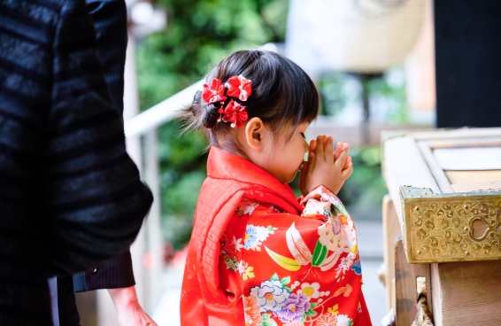 赤い着物の女の子が手を合わせて参拝