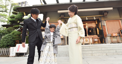 父親と母親に手を掴まれてばんざいをしている着物を着た七五三の五歳児